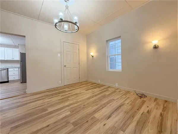 an empty room with wooden floor cabinet and windows