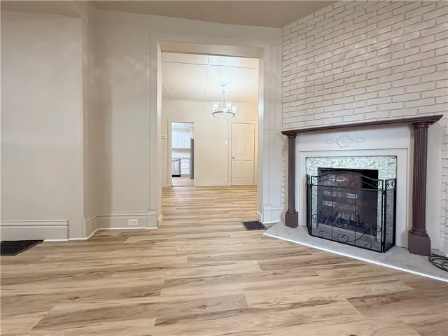 a view of an empty room with wooden floor and fireplace