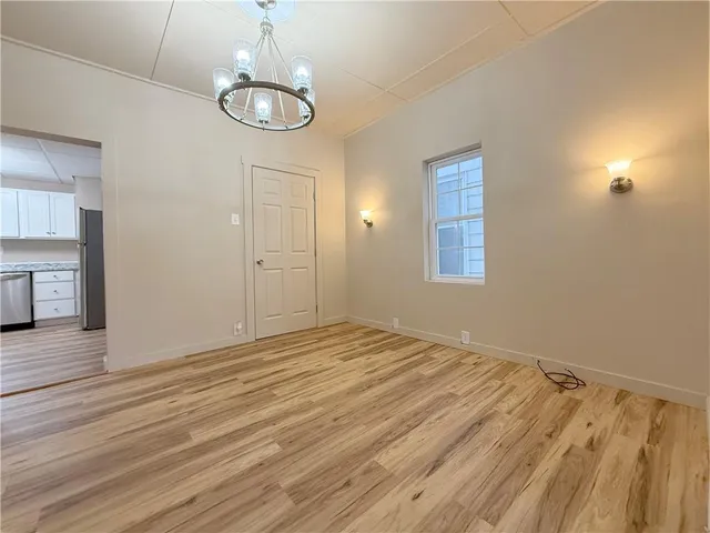 an empty room with wooden floor cabinet and windows