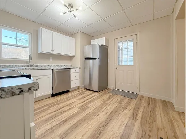a kitchen with granite countertop a stove a sink and white cabinets with wooden floor
