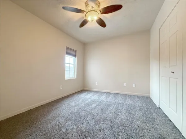 an empty room with chandelier fan and windows