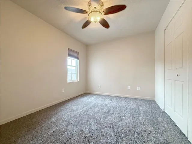 an empty room with chandelier fan and windows