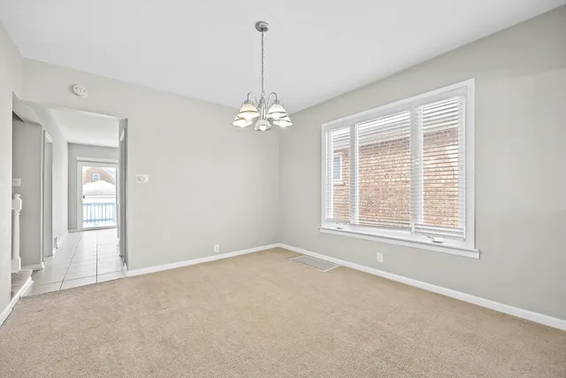 an empty room with chandelier fan and windows