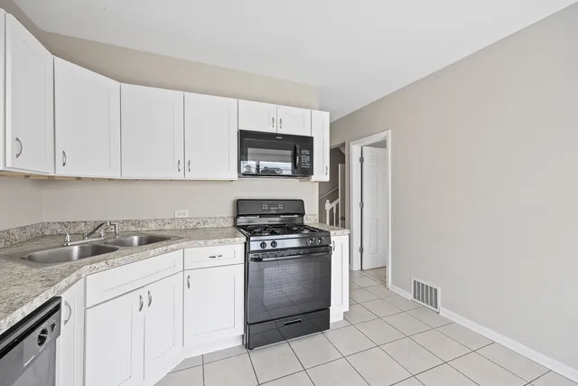 a kitchen with granite countertop white cabinets and stainless steel appliances