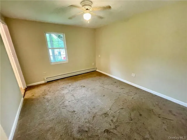 an empty room with a chandelier fan and windows