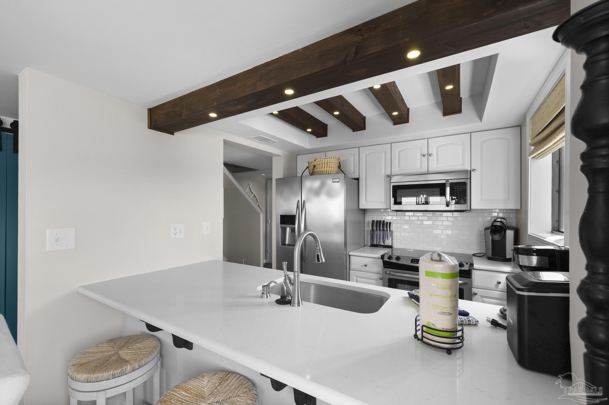 900 Fort Pickens Road, Unit 426 Pensacola Beach, FL 32561 - Photo 18 of 60 a kitchen with stainless steel appliances kitchen island granite countertop a sink a stove and white cabinets