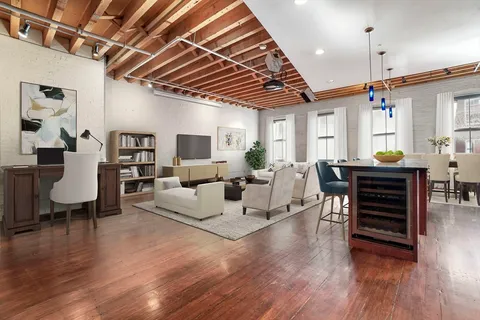 a living room with furniture a wooden floor and next to a window