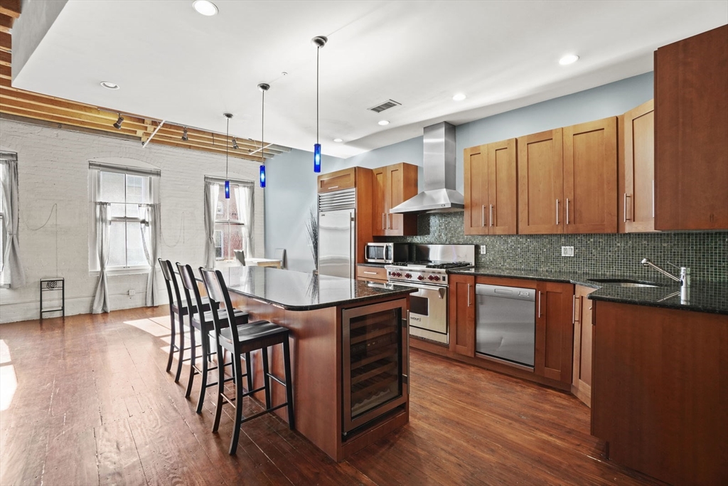 96 South Street, Unit 3 Boston, MA 02111 - Photo 6 of 17 a kitchen with stainless steel appliances granite countertop a table chairs sink and wooden floor