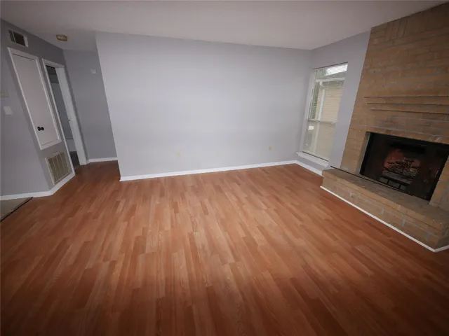 a view of an empty room with wooden floor and a fireplace