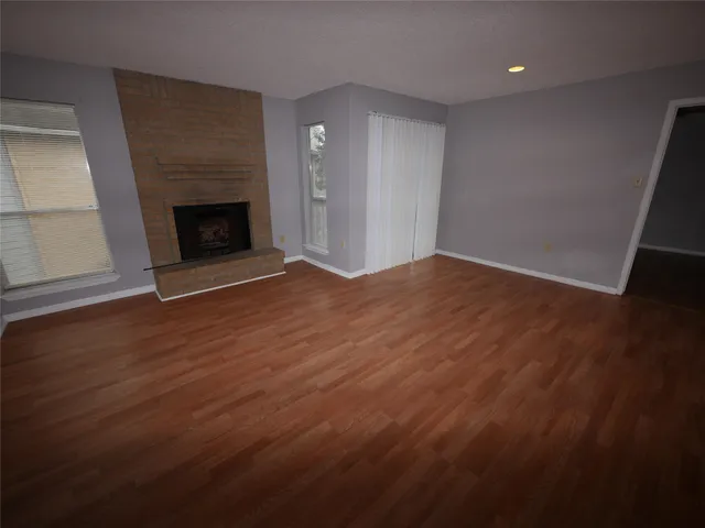 a view of empty room with wooden floor and fireplace
