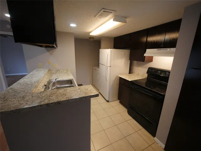 a kitchen with granite countertop a refrigerator and a stove top oven