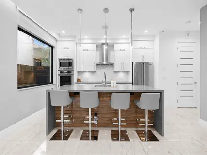 a kitchen with stainless steel appliances kitchen island granite countertop a dining table chairs and sink