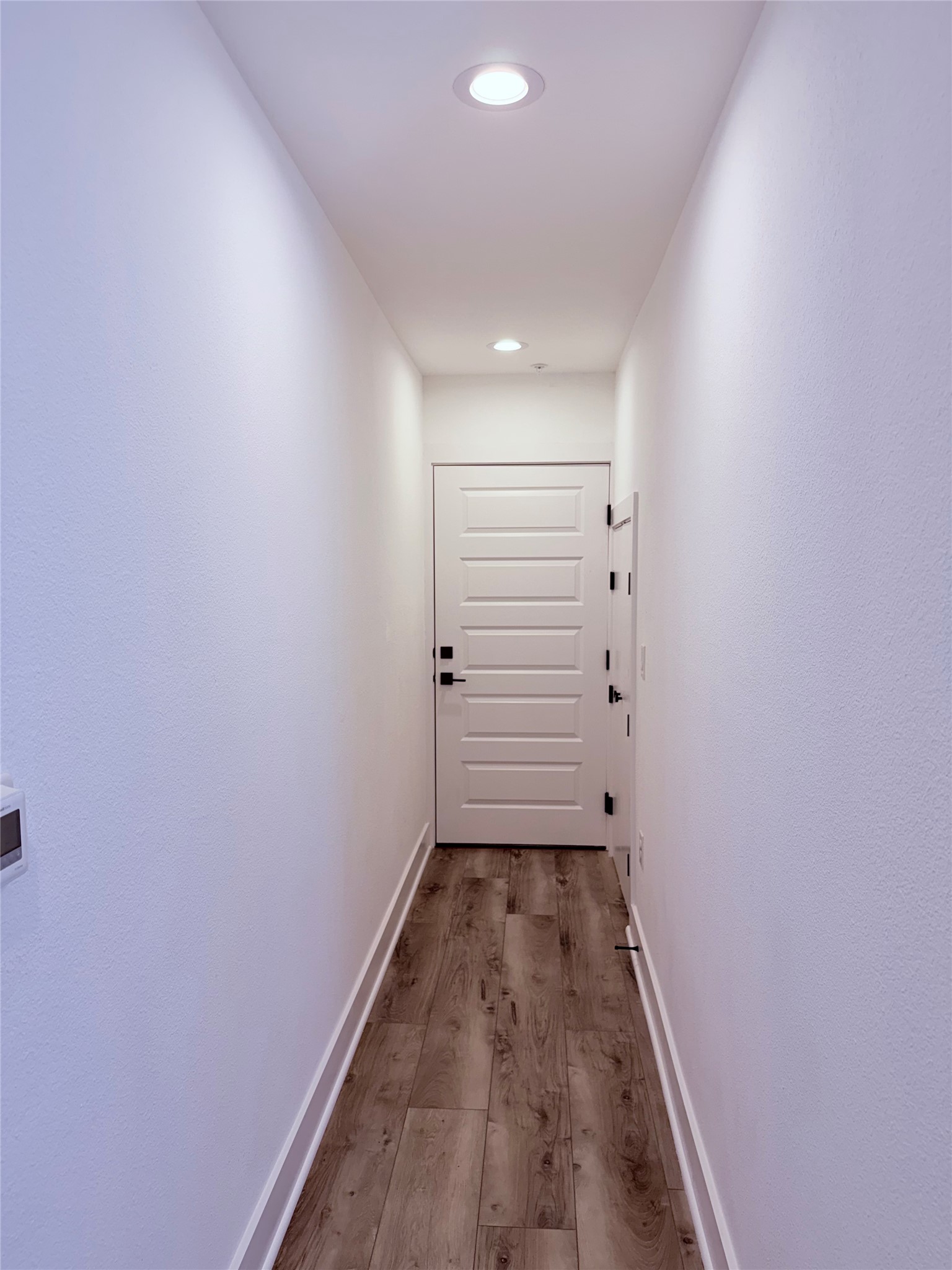 1417 Kramer Lane, Unit 7 Austin, TX 78758 - Photo 22 of 24 Recessed lighting illuminates this hallway with wood flooring and pristine white doors.