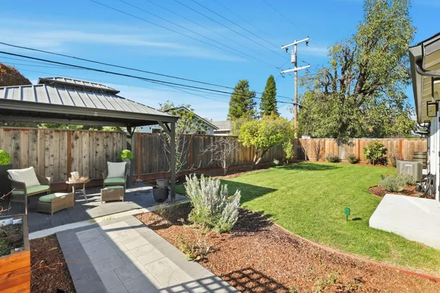 a view of a patio with table and chairs potted plants and large tree