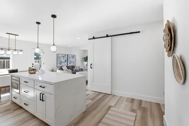 a open kitchen with kitchen island a refrigerator a stove a sink and dishwasher with wooden floor