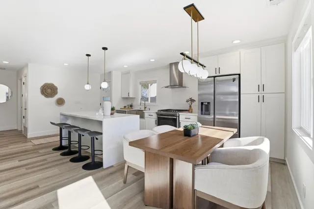 a kitchen with stainless steel appliances kitchen island granite countertop a table chairs and a wooden floor