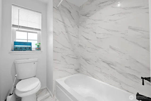 a white toilet sitting next to a bath tub