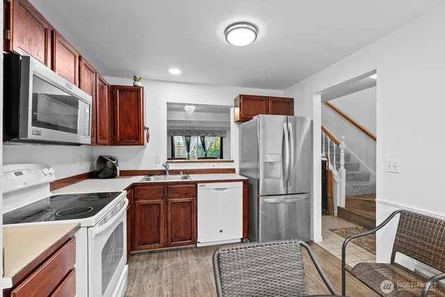 a kitchen with stainless steel appliances granite countertop a refrigerator a stove a sink and a microwave