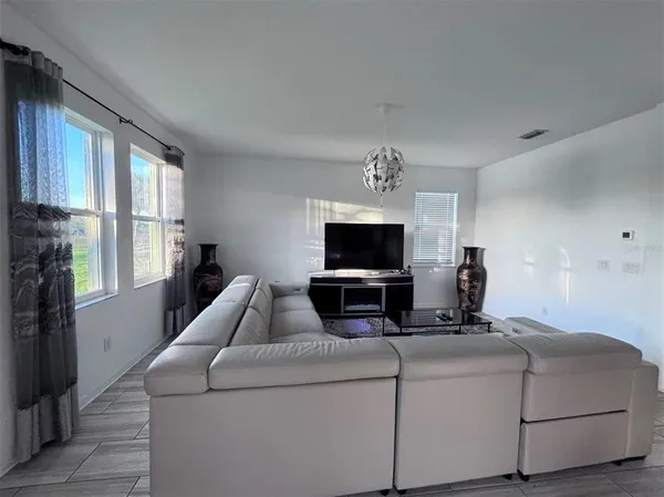 a living room with furniture a flat screen tv and a window