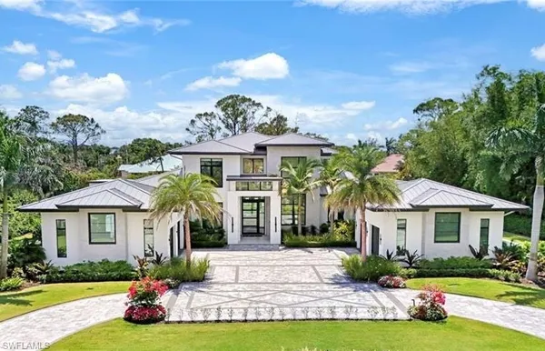 a front view of a house with a yard and potted plants