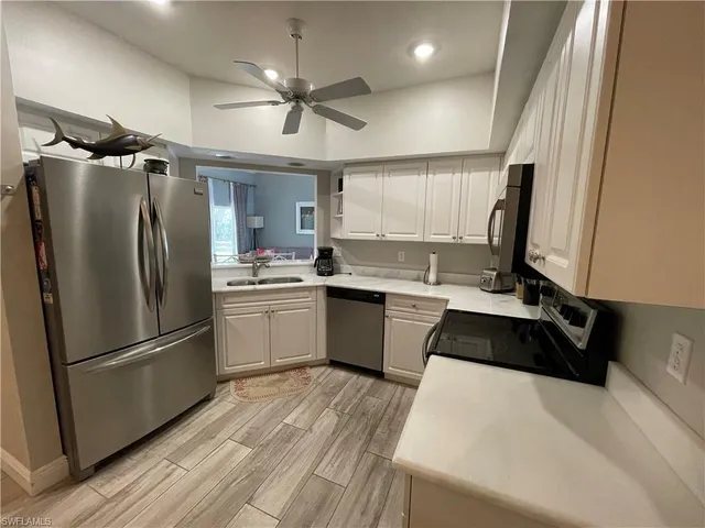 a kitchen with a refrigerator a sink and white cabinets