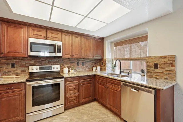 a kitchen with stainless steel appliances granite countertop wooden cabinets stove top oven and sink