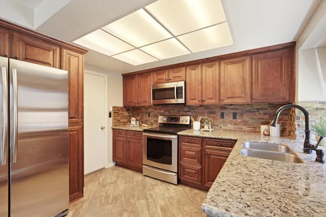 a kitchen with stainless steel appliances granite countertop a refrigerator a stove top oven a sink and dishwasher