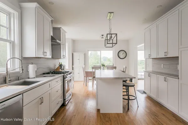 a kitchen with stainless steel appliances granite countertop a stove a sink dishwasher a refrigerator cabinets and wooden floor