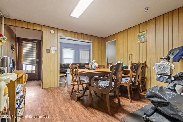 a view of dining room and livingroom with furniture wooden floor a rug a painting and a chandelier