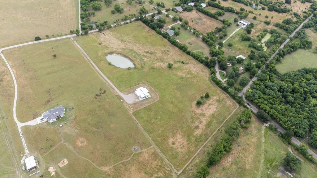 1161 Alsdorf Road Ennis, TX 75119 - Photo 9 of 28 Expansive rural property featuring a primary residence with an asphalt driveway, a secondary structure, and a distinct pond