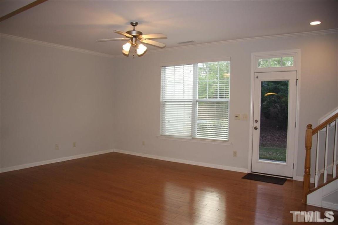 139 Skyros Loop Cary, NC 27519 - Photo 6 of 30 an empty room with wooden floor chandelier fan and windows