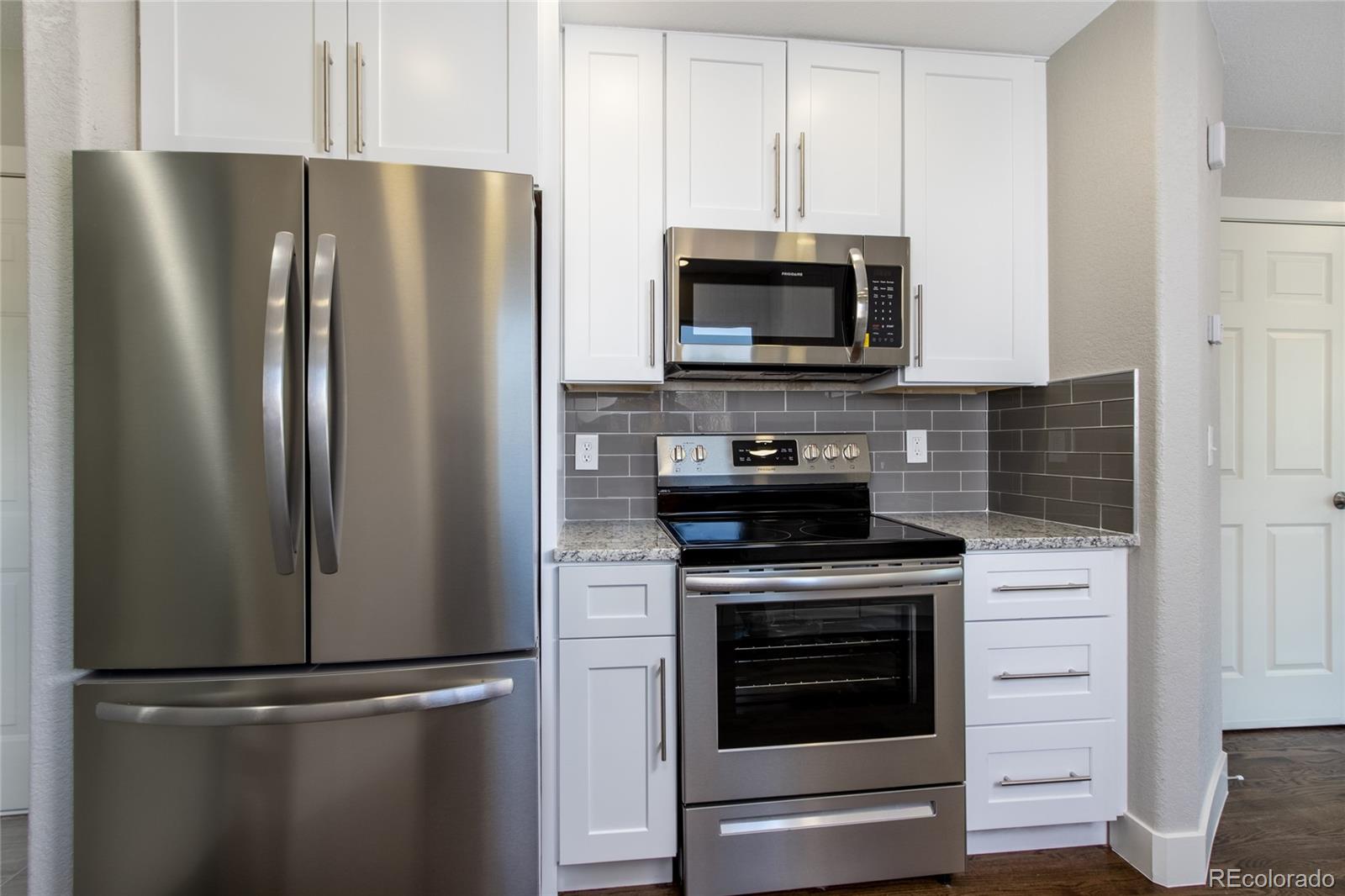1589 Spring Water Way Highlands Ranch, CO 80129 - Photo 12 of 40 a kitchen with stainless steel appliances white cabinets white stove a microwave and a refrigerator