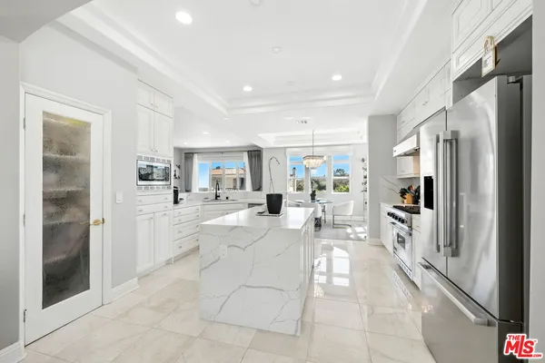 a large white kitchen with cabinets a sink and stainless steel appliances