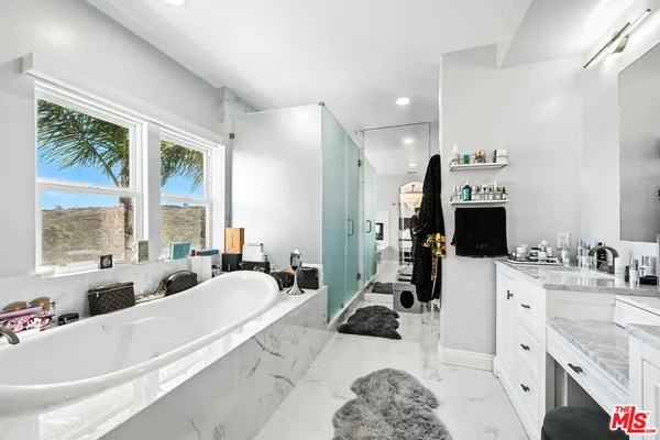 a large white bathroom with a large window sink and mirror