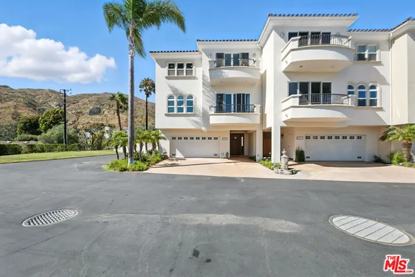a view of a white house with a yard and potted plants