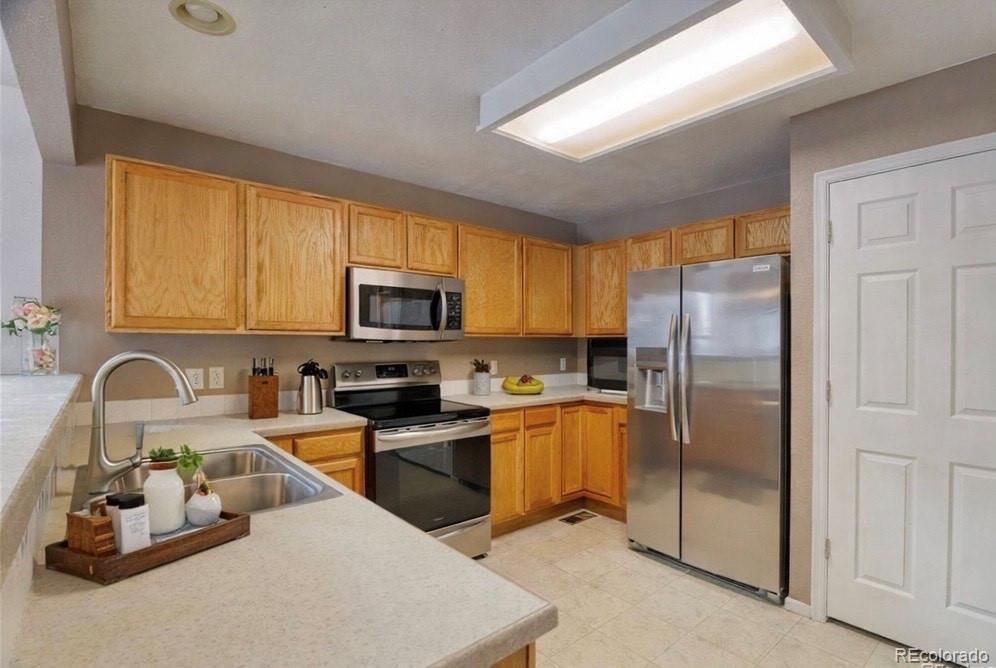 3819 South Rome Way Aurora, CO 80018 - Photo 11 of 32 a kitchen with stainless steel appliances granite countertop a refrigerator a stove top oven a sink and dishwasher