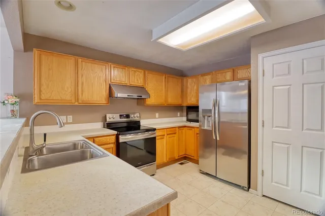 a kitchen with stainless steel appliances granite countertop a sink a stove and refrigerator