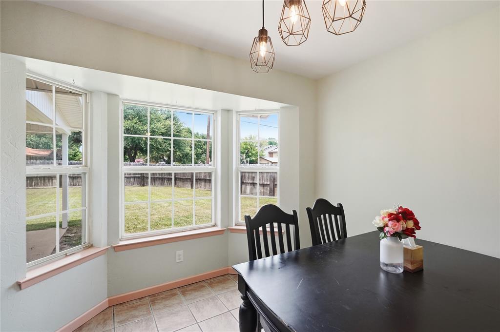 837 Springdale Road Bedford, TX 76021 - Photo 12 of 28 Dining area featuring a bay window with multiple panes, tile flooring, and three geometric pendant light fixtures