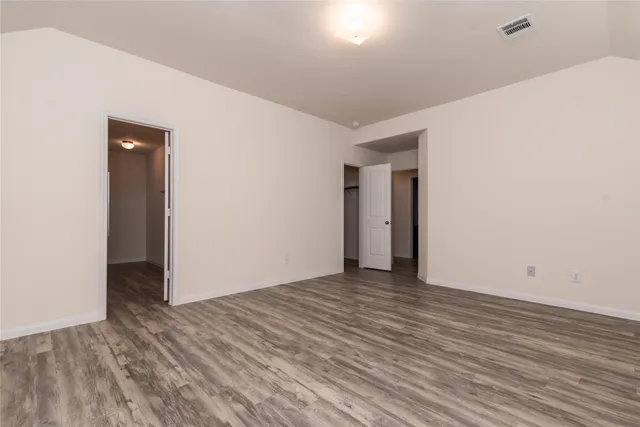 a view of an empty room with wooden floor and closet
