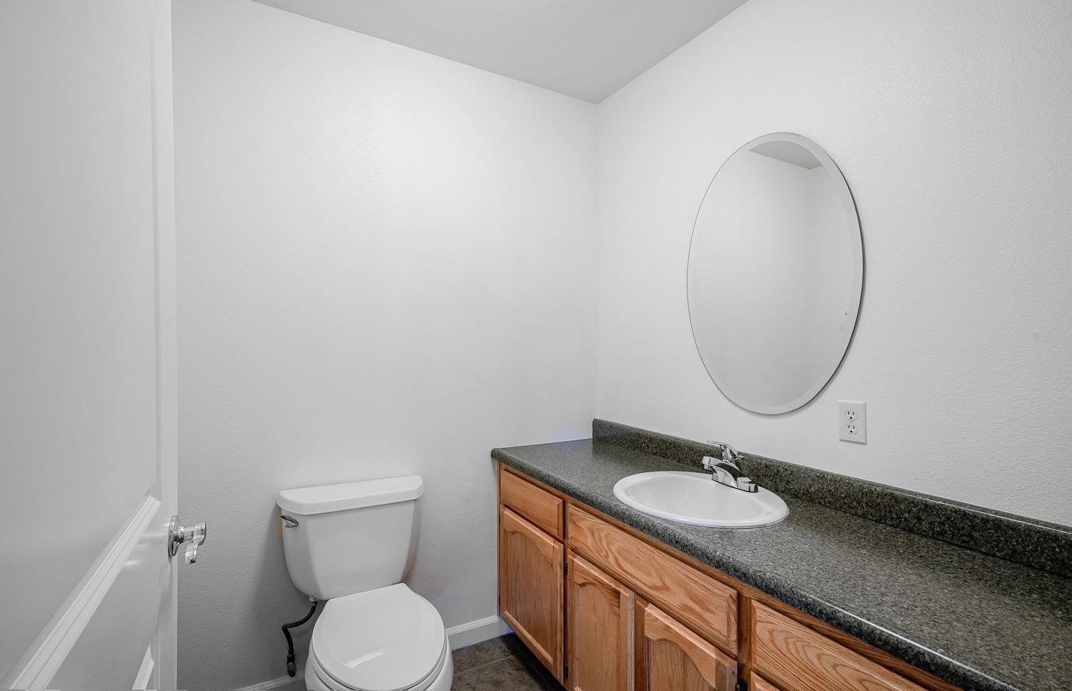 37491 Verde Avenue Madera, CA 93636 - Photo 41 of 66 a bathroom with a granite countertop toilet sink and mirror