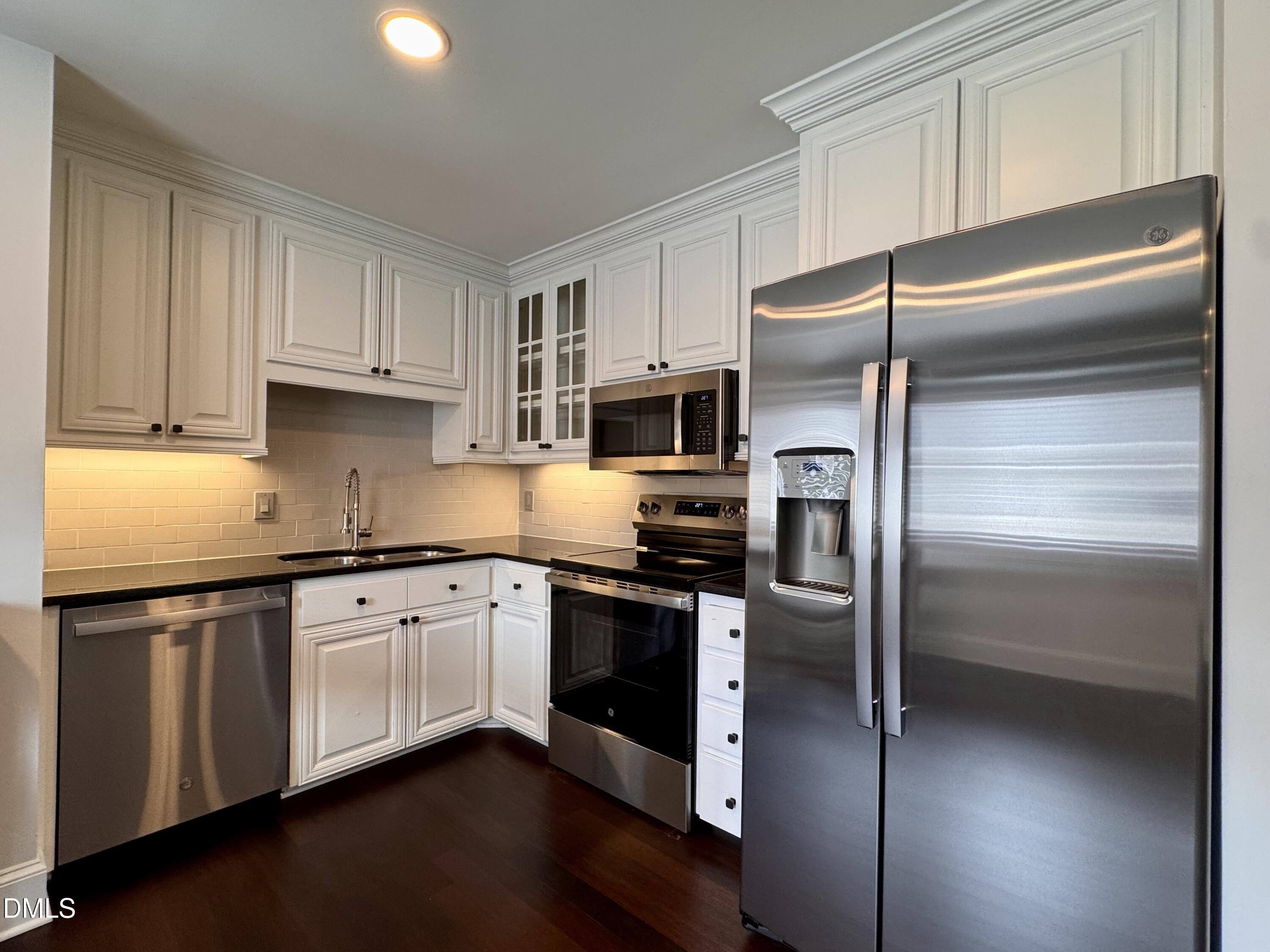 2204 Stafford Avenue, Unit 202 Raleigh, NC 27607 - Photo 4 of 15 a kitchen with a refrigerator stainless steel appliances wooden floor and cabinets