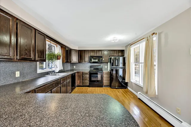 a kitchen with stainless steel appliances granite countertop a refrigerator a stove and a sink with wooden floor