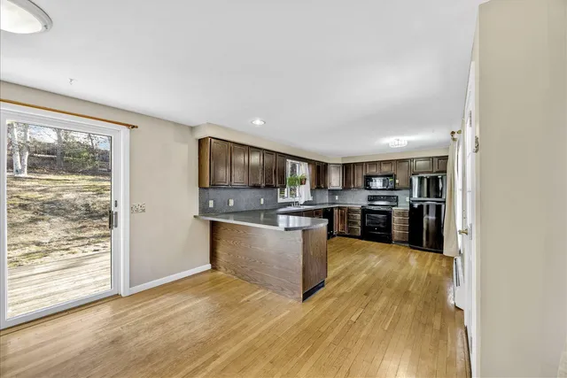 a large kitchen with stainless steel appliances wooden floor and a large window