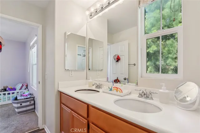 a bathroom with a double vanity sink mirror and next to a window