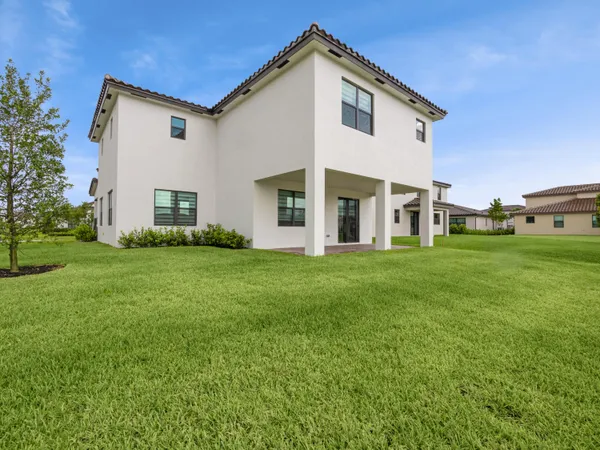 a view of a white house with a big yard and large trees