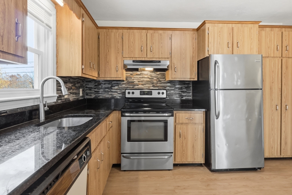 a kitchen with granite countertop a refrigerator stove and sink