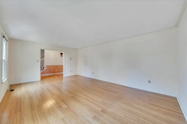 an empty room with wooden floor chandelier and windows