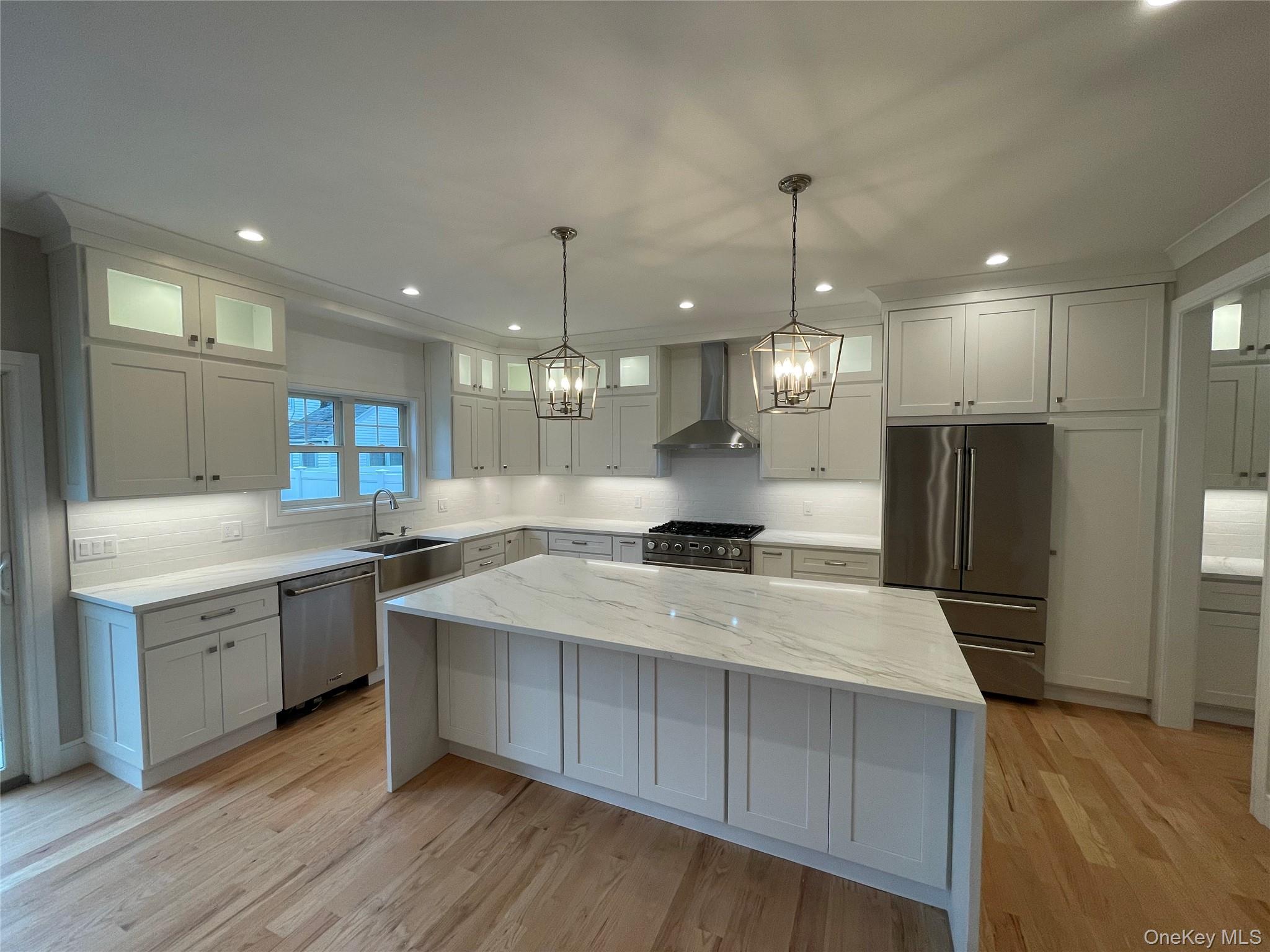 477 Andrews Road, Unit LOT A Mineola, NY 11501 - Photo 5 of 21 a large kitchen with stainless steel appliances a large center island wooden floor and a sink