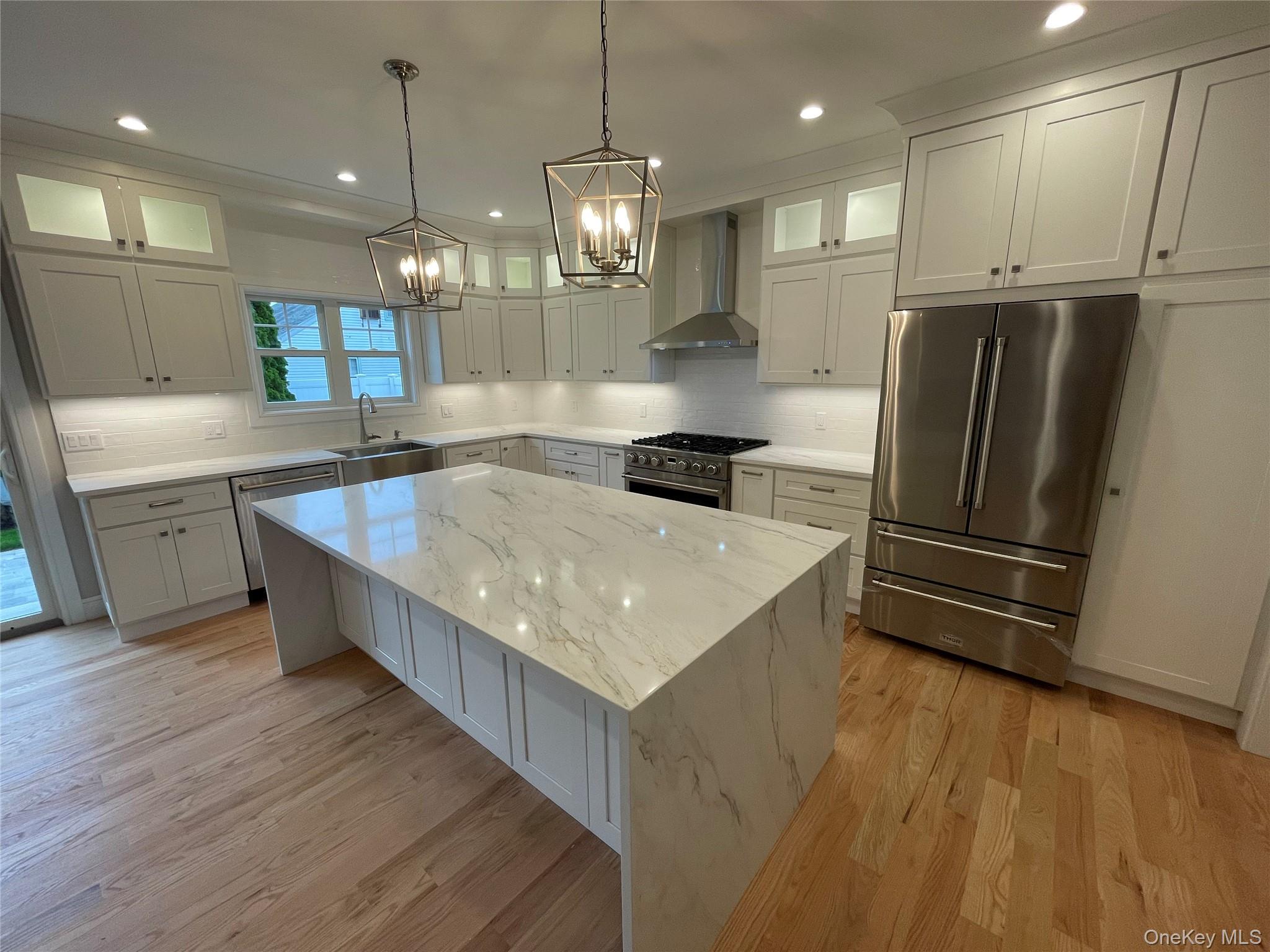 477 Andrews Road, Unit LOT A Mineola, NY 11501 - Photo 6 of 21 a large kitchen with kitchen island a large counter top space a sink stainless steel appliances and cabinets