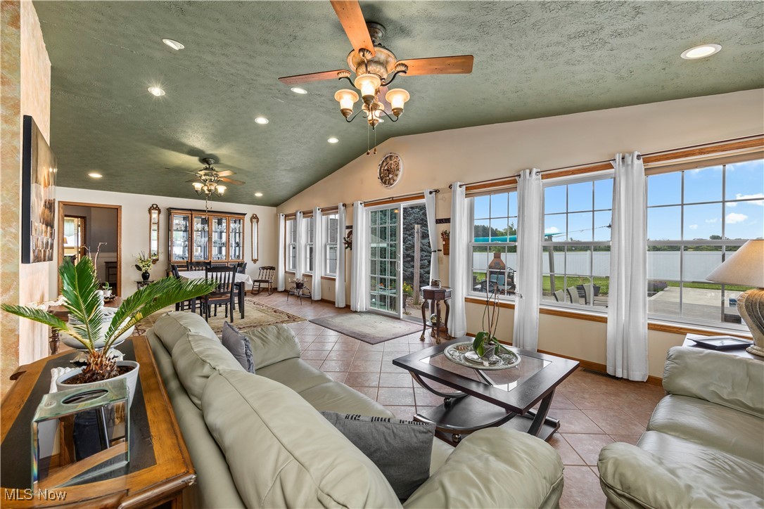 47147 Merriam Road Wellington, OH 44090 - Photo 9 of 49 Sunroom room featuring a ceiling fan, plenty of natural light, recessed lighting, lofted ceiling, and a water view
